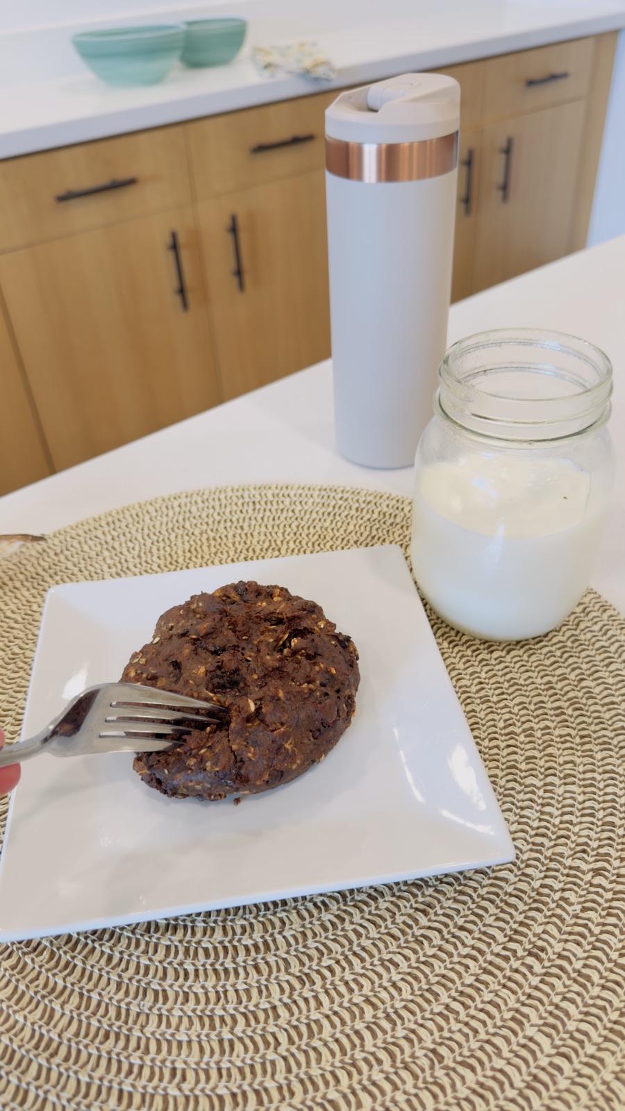 A fork resting in a chocolate cookie on a breakfast plate